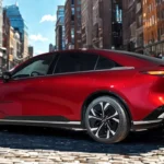 2026 Mazda 6e driekwart achteraanzicht in Soul Red Crystal met liftback proporties, LED achterlichten, en randloze ramen op stedelijke straat