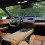 2026 Mazda 6e interieur zijaanzicht met premium tan lederen stoelen, verhoogde middenconsole, zwevend touchscreen display, en hoogwaardige cabinematerialen