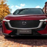 2026 Mazda 6e vooraanzicht in Soul Red Crystal met Kodo design, LED signature grille, en aerodynamische styling in stedelijke omgeving