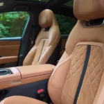 2026 Mazda 6e voorstoelen close-up met gestikt tan Nappa leder bekleding met suède inzetstukken en premium stikwerk details in Takumi Plus uitvoering