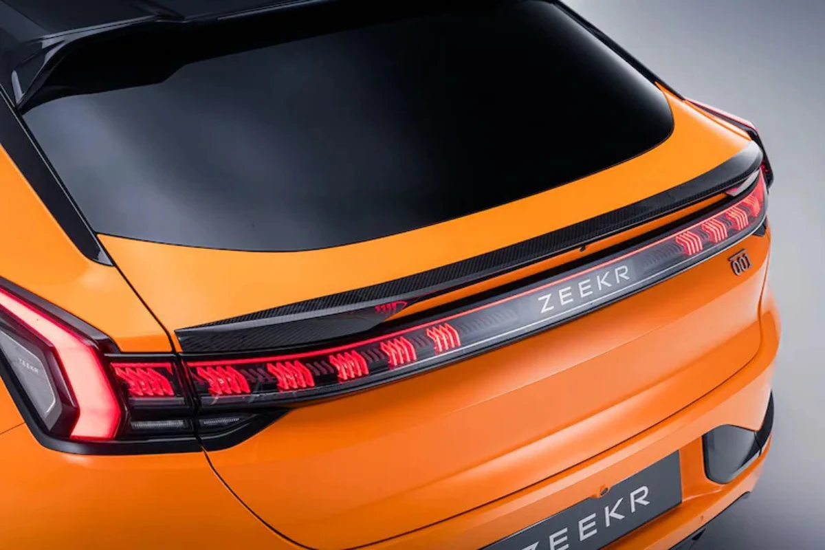 Gedetailleerd aanzicht van Zeekr 001 Sport Edition carbon fiber achterspoiler met geïntegreerde LED achterlichten, Speed Orange lakafwerking en premium carbon fiber weefselstructuur