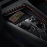 Zeekr 001 Sport Edition middenconsole met draadloze oplaadpad met telefoon, versnellingskiezer, bekerhouders met oranje trim ringen, premium zwarte oppervlakken en geïntegreerde bedieningselementen