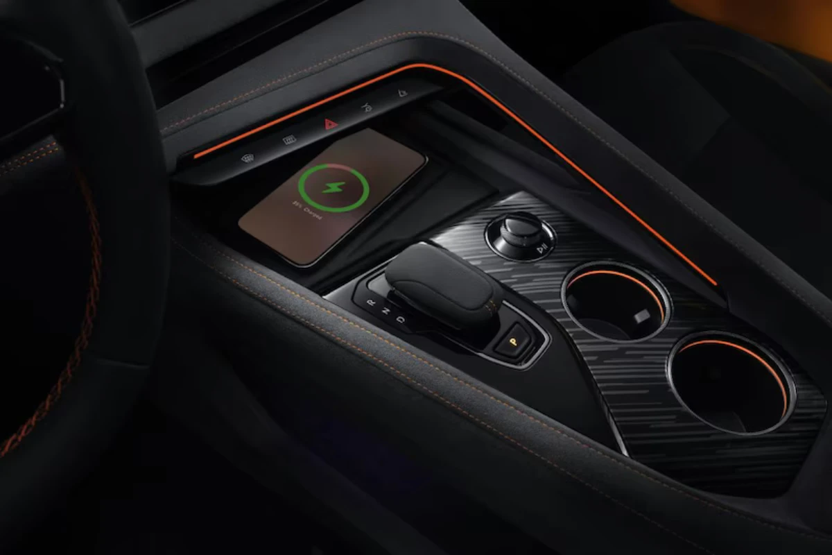 Zeekr 001 Sport Edition middenconsole met draadloze oplaadpad met telefoon, versnellingskiezer, bekerhouders met oranje trim ringen, premium zwarte oppervlakken en geïntegreerde bedieningselementen