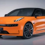 Zeekr 001 Sport Edition schuin vooraanzicht met 22-inch zwarte velgen met oranje remklauwen, Speed Orange lak, carbon fiber voorspoiler elementen en shooting brake silhouet