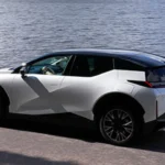 Achter driekwart aanzicht van witte Zeekr X elektrische SUV gepositioneerd bij waterkant met verfijnd achterdesign, premium wielen en elegante verhoudingen