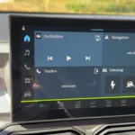 Centrale touchscreen display van 2025 Dacia Bigster met Duitse interface, mediabediening, telefoonconnectiviteit, navigatieopties en klimaatregelingsknoppen eronder