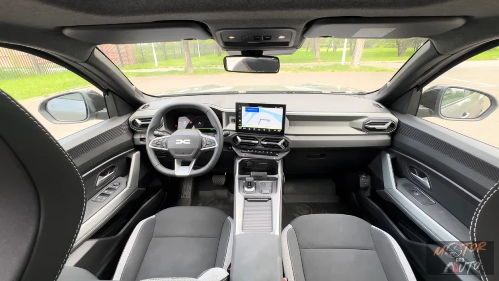 Volledig dashboardzicht van 2025 Dacia Bigster interieur met digitaal instrumentenpaneel, centrale touchscreen, stuurwiel met DC-logo en tweekleurig interieurontwerp met automatische versnelling