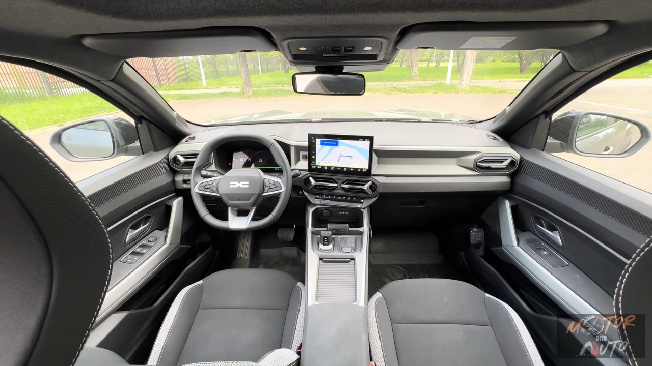 Volledig dashboardzicht van 2025 Dacia Bigster interieur met digitaal instrumentenpaneel, centrale touchscreen, stuurwiel met DC-logo en tweekleurig interieurontwerp met automatische versnelling