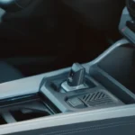 Middenconsole van 2025 Dacia Bigster met handmatige versnellingspook, bekerhouders, opbergvakken en gestructureerde oppervlakken met praktische designelementen