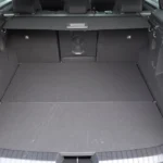 Interieur bagagegebied van 2025 Dacia Bigster met rechtopstaande achterstoelen met donkere vloerbedekking, bagagedeksel, zijpanelen en praktische ophaaghaken met natuurlijke verlichting