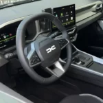 Compleet interieurzicht van 2025 Dacia Bigster met volledig dashboard, middenconsole, stoelen en panoramadak met natuurlijke verlichting die het moderne tweekleurige interieurontwerp belicht