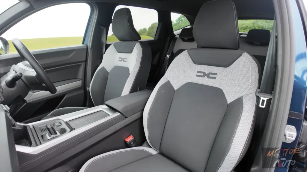 Close-up van 2025 Dacia Bigster voorstoelen met tweekleurige grijs-witte bekleding met geëmbosseerde DC-logo's op rugleuningen en premium stikdetails