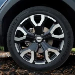 Gedetailleerde close-up van een lichtmetalen wiel van de 2025 Dacia Bigster met zwarte en zilveren afwerking met DC-logo middendop, gemonteerd met Michelin E Primacy band, waarbij wielkasbekleding zichtbaar is
