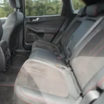 Interieurzicht van de 2025 Ford Kuga met de verschuifbare achterbank met rode stiksels en ruime beenruimte