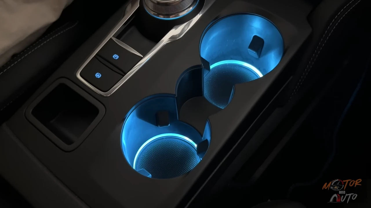 2025 Ford Kuga middenconsole bekerhouders met blauwe sfeer LED verlichting en draadloze telefoon oplaad functionaliteit, die premium interieur verlichtingsontwerp toont