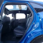 2025 Ford Kuga met passagiersdeur open die ruime interieurcabine, comfortabele zitarrangement en praktische deuropenhoek voor gemakkelijke toegang in stedelijke omgeving toont