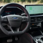 Close-up zicht van 2025 Ford Kuga stuurwiel bedieningselementen en 12,3-inch digitaal instrumentenpaneel met boordcomputer informatie, brandstofverbruik en voertuigstatus