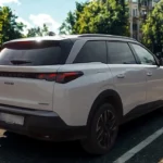 Witte 2025 Peugeot 5008 SUV vanuit achter driekwart hoek met zwart dak, kenmerkende achterlichten en HYBRID badge op stadsstraat