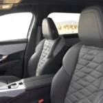 Interieurzicht van de voorstoelen van de 2025 Peugeot 5008 met gestikt bekledingspatroon en panoramadak erboven