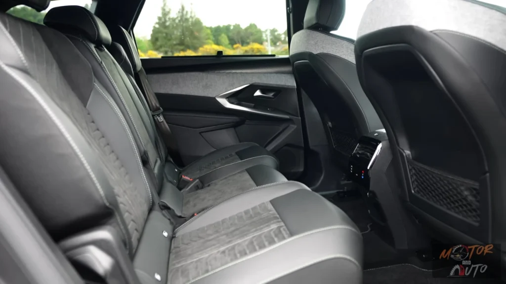 Interieurzicht van de tweede rij stoelen van de 2025 Peugeot 5008 met gestikt bekledingspatroon en individuele armleuningen met raamzicht