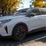 Witte 2025 Peugeot 5008 SUV vanuit voor driekwart hoek op herfst stadsstraat met LED koplampen en 19-inch velgen