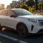 Zijprofiel zicht van witte 2025 Peugeot 5008 SUV met zwart dak bij zonsondergang met volledige lengte en velgenontwerp op stadsstraat