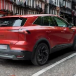 Achter driekwart zicht van 2025 Renault Symbioz met moderne LED achterlichten, achterspoiler en SYMBIOZ badge op stadsstraat