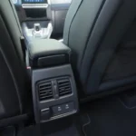 Achterpassagiers bedieningsgebied in de 2025 Renault Symbioz met klimaatbedieningsroosters, dubbele USB-C oplaadpoorten en 12V stromaansluiting voor verbeterd passagierscomfort en connectiviteit.