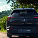 2025 Suzuki e Vitara achteraanzicht met LED-achterlichten, spoiler en e VITARA-badge tegen groene landschapsachtergrond