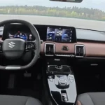 2025 Suzuki e Vitara volledig dashboard met dubbele schermen, fysieke klimaatbediening, bruine afwerking en middenconsole
