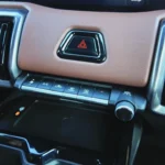 2025 Suzuki e Vitara klimaatbedieningsknoppen met AC, ontdooier, ventilator en temperatuurbediening met bruin dashboard