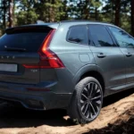 2026 Volvo XC60 achter driekwart zicht met verduisterde achterlichten, lichtmetalen velgen, T8 badge en elegante SUV proporties in bosomgeving