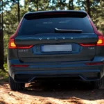 2026 Volvo XC60 achterzicht met VOLVO letters, XC60 en T8 plug-in hybrid badges en verduisterde achterlichten in bosomgeving