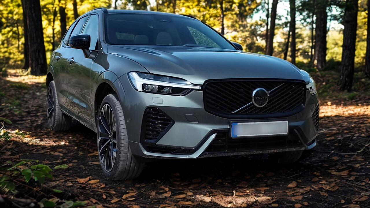 2026 Volvo XC60 dynamische voor driekwart hoek met vernieuwd grille ontwerp, zelfverzekerde houding en Forest Lake metallic lak op bosweg