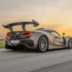 Dynamische achter driekwart zicht van Hennessey Venom F5 Revolution LF in champagne metallic lak met grote achterspoiler, agressieve aerodynamica, en bewegingsonscherpte op circuit