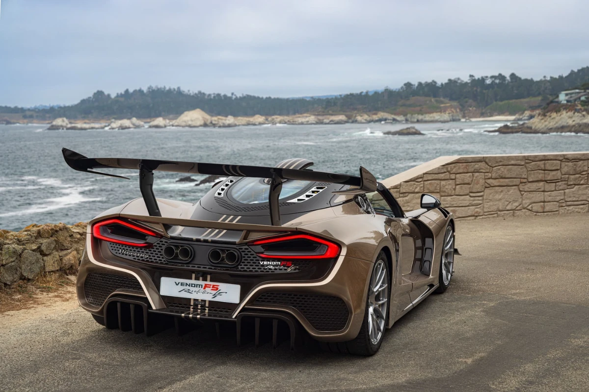 Achterzicht van Hennessey Venom F5 Revolution LF gepositioneerd op kustweg met Pacifische Oceaan en kliffen op achtergrond, kenmerkende achterlichten en achter aerodynamica tonend