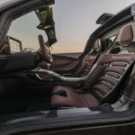 Passagierszijde interieurzicht van Hennessey Venom F5 Revolution LF met bruine leren kuipstoelen met Hennessey branding, koolstofvezel accenten, en premium cabine materialen