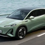 Hongqi EHS5 elektrische SUV in beweging op waterfront weg met dynamische prestaties, groene exterieur kleur, en modern aerodynamisch design met rode accent streep