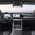 Omoda 9 SUV interieur met zwarte leren stoelen, dubbele 12,3-inch digitale displays, stuurwiel met Omoda-branding, middenconsole met draadloze oplaadpad en panoramisch glazen dak