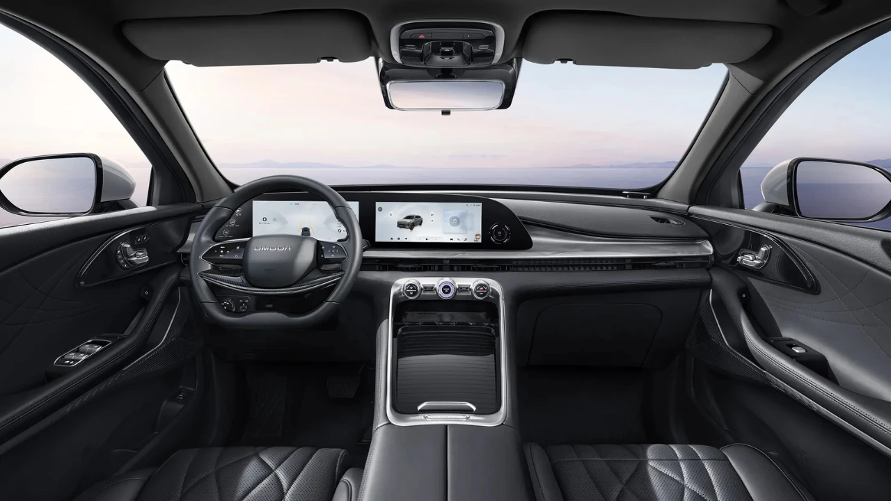 Omoda 9 SUV interieur met zwarte leren stoelen, dubbele 12,3-inch digitale displays, stuurwiel met Omoda-branding, middenconsole met draadloze oplaadpad en panoramisch glazen dak