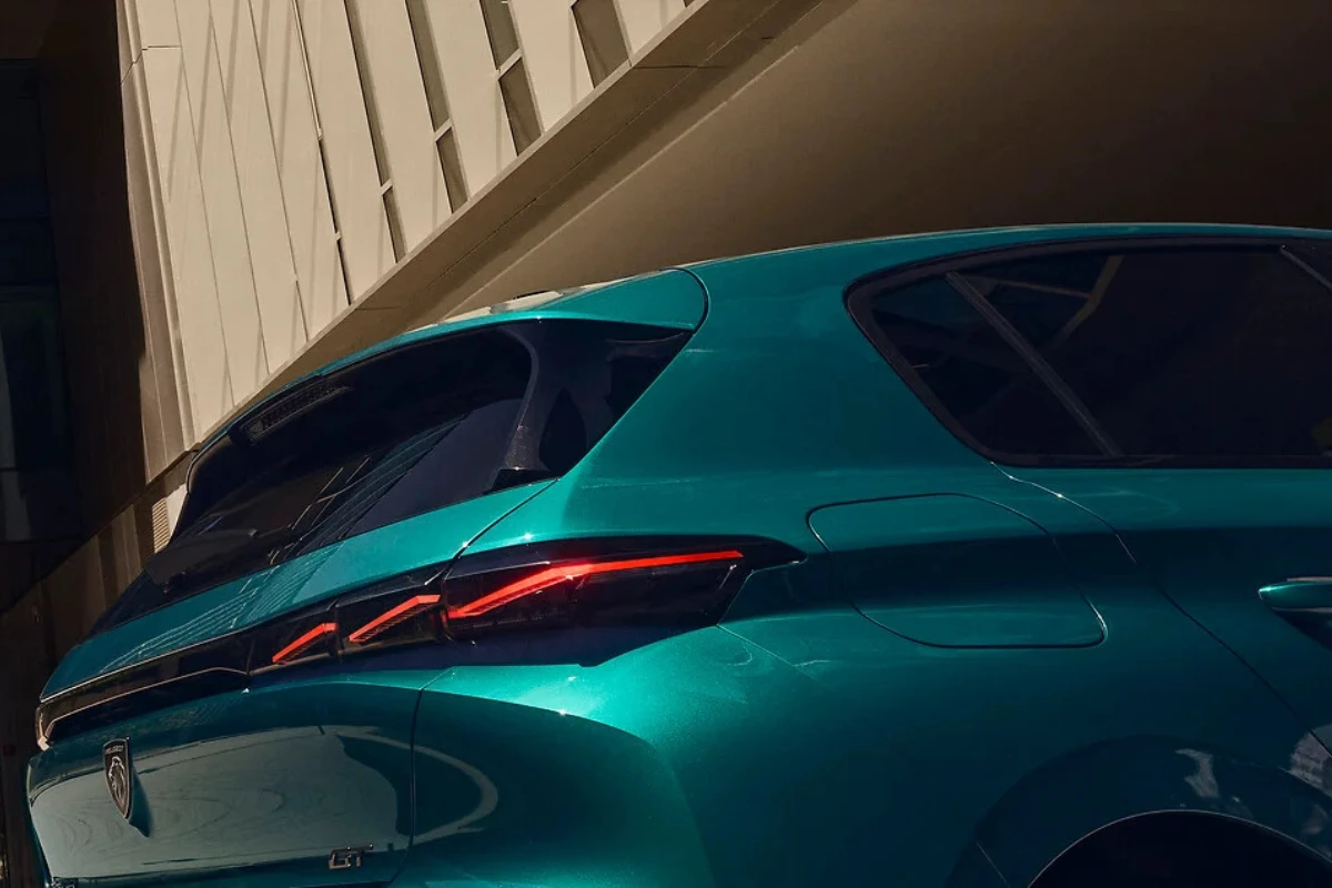 Achter driekwart aanzicht van de 2025 Peugeot 308 facelift in teal groen met diagonale LED achterlichtstrips en strak achterdesign