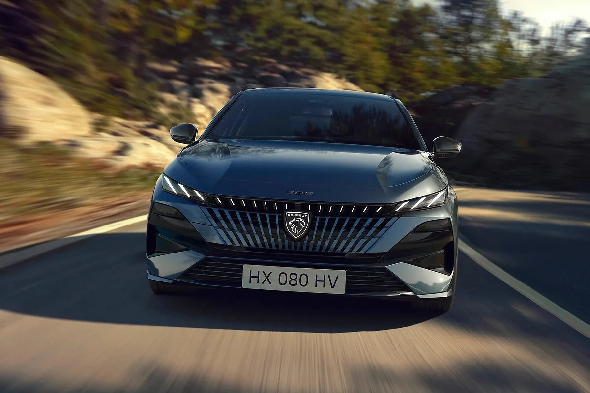 Dynamisch vooraanzicht van de 2025 Peugeot 308 facelift in grijs met verfijnde drieklauw LED-design en moderne front styling tijdens het rijden