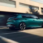 Zijaanzicht van de 2025 Peugeot 308 facelift in teal groen met nieuwe diamant-geslepen lichtmetalen velgen en aerodynamisch carrosserieontwerp tijdens het rijden