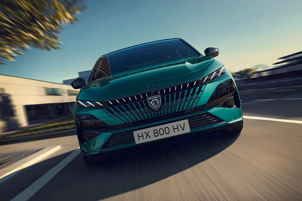 Dynamisch vooraanzicht van de 2025 Peugeot 308 facelift in teal groen met nieuw gesplitst koplampdesign, drieklauw LED-signatuur en aerodynamische grille tijdens het rijden