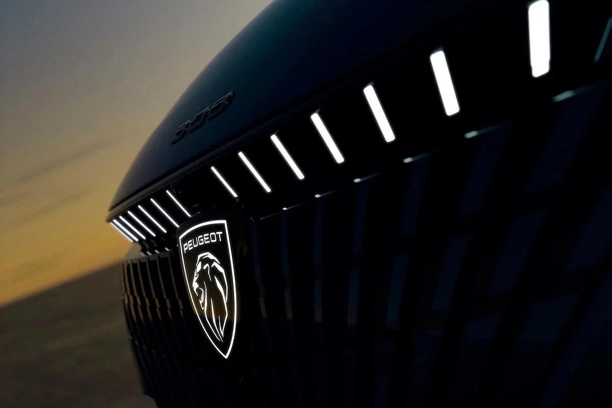 Close-up detail van het verlichte Peugeot leeuw embleem op de nieuwe 308 facelift met LED lichtstrips erboven die een premium verlichtingssignatuur creëren