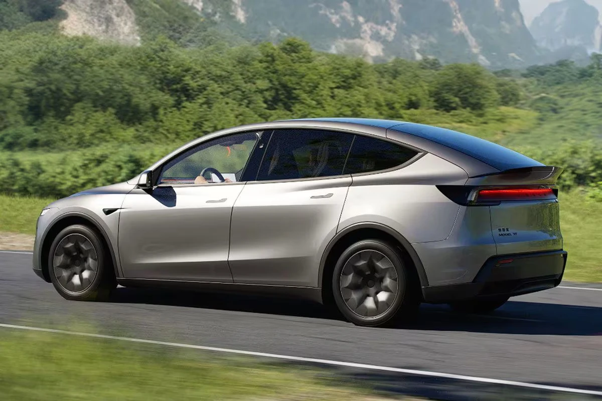 Zilveren Tesla Model YL elektrische SUV rijdend op bergweg met verlengd zijprofiel, langere wielbasis en aerodynamisch ontwerp van het 6-zits familie voertuig