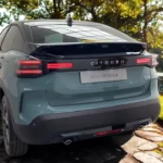 Achter driekwart aanzicht van de 2025 Citroën C4 die het vernieuwde achterontwerp toont met nieuwe 3D LED achterlichten, CITROËN letters over de achterklep, geïntegreerde achterspoiler en dubbele uitlaat openingen. De facelift bevat herontworpen achterverlichting signatuur en behoudt het coupe-SUV silhouet.