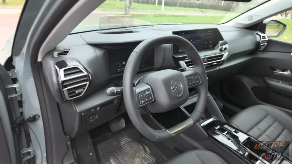 Bestuurderscockpit zicht van 2025 Citroën C4 met digitaal instrumentenpaneel, lederen stuurwiel met vernieuwd logo en fysieke klimaatregelaars