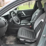 Voorpassagiersruimte van 2025 Citroën C4 met gewatteerde comfortstoelen met driekleurige bekleding en handmatige verstelling
