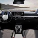 Volledig panoramisch interieur aanzicht van 2025 Kia Stonic met compleet dashboard, dubbele schermen, stuurwiel, stoelen met gewatteerd patroon en schilderachtig uitzicht door voorruit